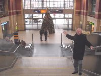 Helmut Bargfrede, Vorstand der Werbegemeinschaft Kieler Hauptbahnhof, zeigt auf die glserne Wand, an der die Grobildleinwand  befestigt wird. Die Treppen bilden die "Tribne", und  auch der gesamte ebenerdige Platz ist Zuschauerraum.